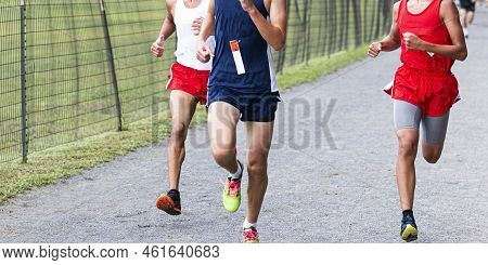 Three High School Cross Country Runners Racing Each Other On The Final Straight On A Gravel Path Nex