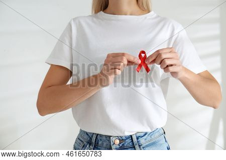 Woman Holding Red Awareness Ribbon On Light Background, Closeup. World Aids Disease Day