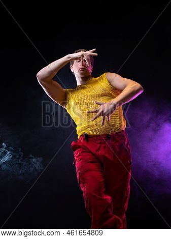 A Young Muscular Man In A Bright Outfit Poses In A Pretentious Pose, Style And Grotesque. Attractive