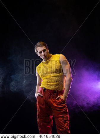 A Young Muscular Man In A Bright Outfit Poses In A Pretentious Pose, Style And Grotesque. Attractive