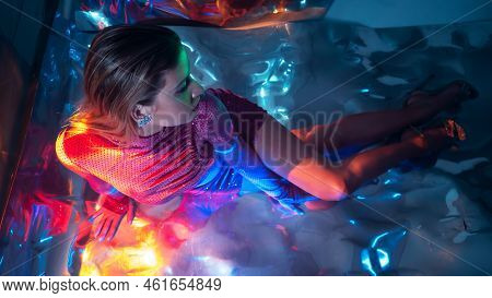Glamorous Portrait Of A Young Beautiful Blonde In A Stylish Scarlet Short Dress, Sitting On The Floo