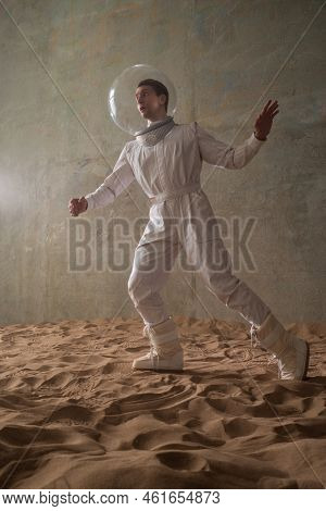 Fear Of The Unknown On Alien Planets. An Astronaut In A White Spacesuit Walks Through An Abandoned C