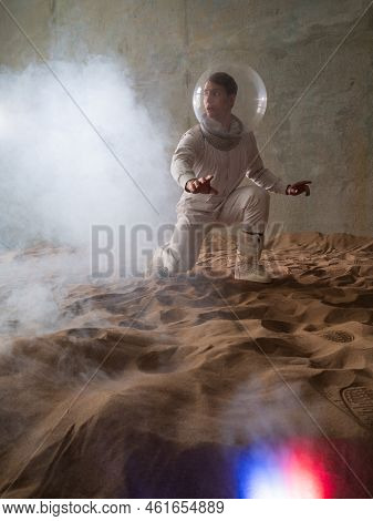 Fear Of The Unknown On Alien Planets. An Astronaut In A White Spacesuit Walks Through An Abandoned C