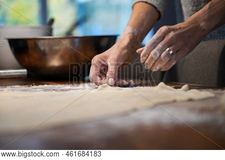 Low Angle View Of A Woman Preparing Homemade Pastry Dough For A Strudel Or Pie, Stetching It On A Fl