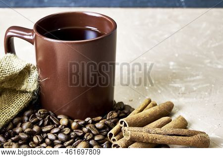 Coffee Beans Spilled Out Of A Canvas Bag Of Cinnamon And A Coffee Mug Onto A Table With A Place Of C