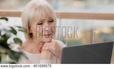 Happy Calm Mature Middle Aged Woman Sitting Resting Relaxing Holding Hands Under Chin Looking At Lap