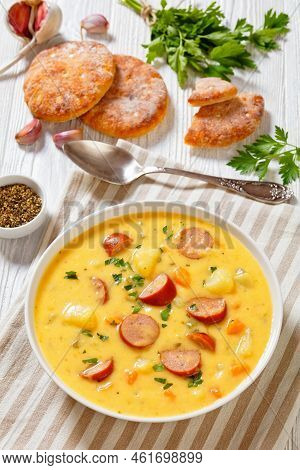 Kartoffelsuppe, German Potato Soup With Sausages In White Bowl On White Wooden Table, Vertical View 