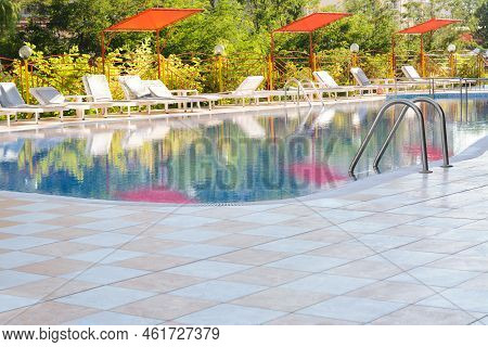 Outdoor Swimming Pool And Many Empty Loungers At Resort On Sunny Day