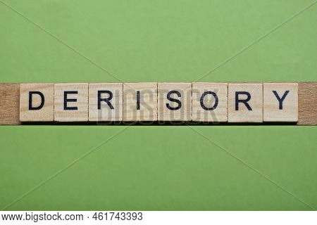 Word Derisory Made Of Small Gray Wooden Letters On A Green Paper Background