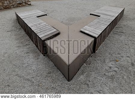 A Bench Made Of One Piece Of V-shaped Concrete. A Park Bench In The Shape Of An Arrow As A Mirrored 