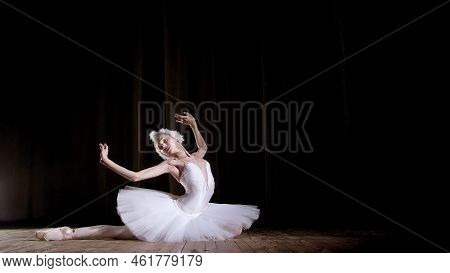 In Rays Of Spotlight, On The Stage Of The Old Theater Hall. Young Ballerina In Suit Of White Swan An
