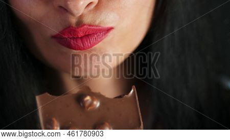 Sweet Temptation. Cropped Closeup Of A Red Lipped Female Biting On A Chocolate, Lips Of Beautiful Se