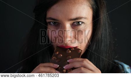 Portrait Of A Sexy Brunette Woman With Red Lips Who Eroticly And Playfully Eats Black Chocolate With