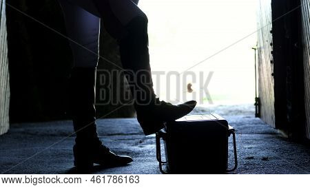 Against The Light, In The Stable, Outline, Figure Of The Girl. She Dresses Boots For Riding