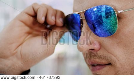 Close-up, Portrait Of Handsome Young Man Trying On Blue Sunglasses At Optical Store, Optician Retail