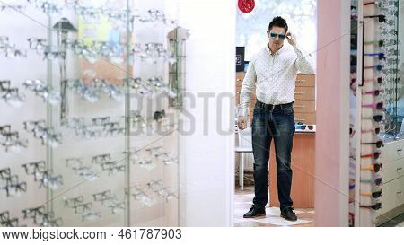 Handsome Young Man Choosing Eyeglasses In Optical Store. Optics, Optician Retail Store. Health Care,