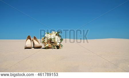 Summer, Desert, Wedding Female Beige Heels Stand On The Sand, Next To The Wedding Bouquet. Day, Agai