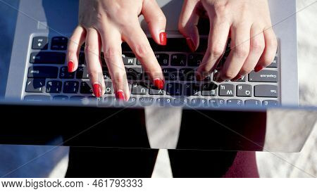 Summer, Sea Beach. Close-up On Top Of Female Hands With Bright Red Manicure, Type On The Laptop Keyb