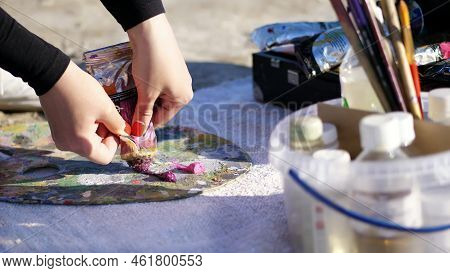 Close-up, Female Hands With Bright Red Manicure. The Artist Squeezes Some Burgundy Paint From A Tube