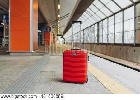 Forgotten Travel Bag On The Train Station. Red Suitcase On Empty Station Platform. Travel And Vacati