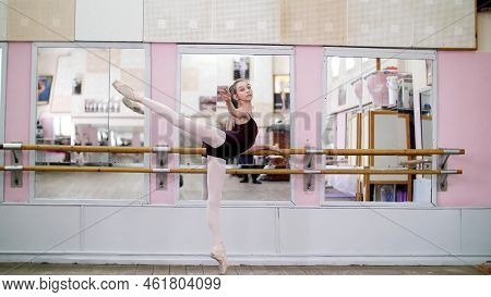 In Dancing Hall, Young Ballerina In Purple Leotard Performs Developpe Attitude On Pointe Shoes, Rais