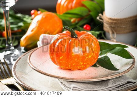 Autumn Table Setting With Plate, Pumpkin And Candles At Wooden Table. Thanksgiving Food Festive Dinn