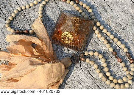 A Top View Image Of A Carnelian Orgonite Pyramid With Mala Meditation Beads.