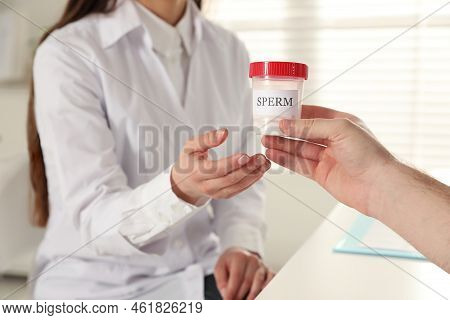 Donor Giving Container Of Sperm To Doctor In Hospital, Closeup