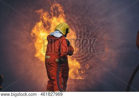 Firefighter Rescue Training In Fire Fighting Extinguisher. Firefighter Fighting With Flame Using Fir