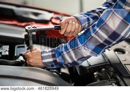 Female Auto Mechanic Unscrewing A Nut To Replace A Car Spark Plug.