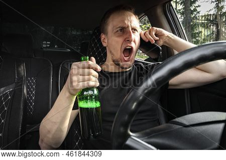 Emotianal Drunk Aggressive Driver With A Bottle Of Beer Driving A Car Swears On The Phone. Alcohol D