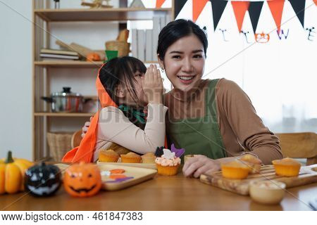 Young Girl And Mother At Halloween Making Treats And Cupcake On Table. Happy Halloween Day