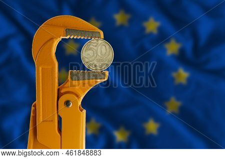50 Kazakhstani Tenge Coin Clamped In An Orange Plumber Wrench On The Background Of The European Flag