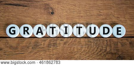 Gratitude Symbol. The Concept Word Gratitude On White Circles. Beautiful Wooden Table, Wooden Backgr
