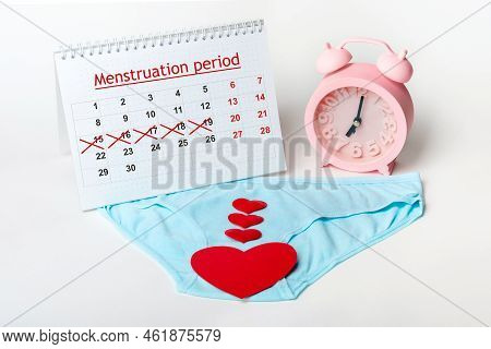 Women's Underwear With Red Hearts, An Alarm Clock And A Menstrual Calendar With Crossed-out Dates On