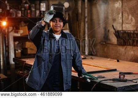 Waist Up Portrait Of Multiethnic Female Welder Smiling At Camera In Industrial Factory Workshop