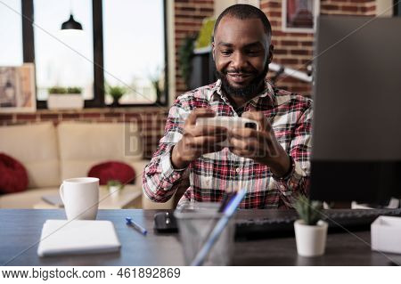 Young Adult Playing Video Games On Mobile Phone, Having Fun With Online Gaming Competition And Worki