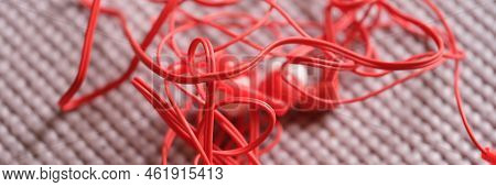Red Wired Headphones On A Gray Background. Closeup Of Tangled Tangled Tied Ears With White Headphone