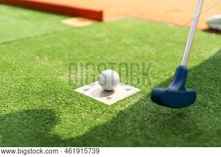 A Club Prepares To Hit A Ball During A Mini Golf Game