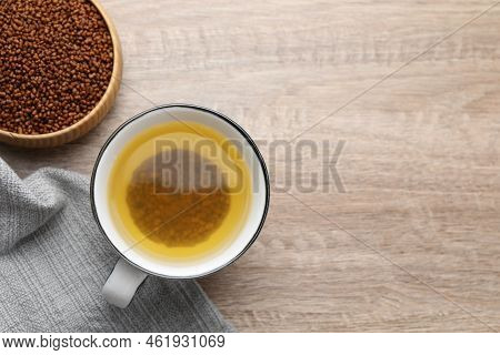 Buckwheat Tea In Cup And Bowl With Granules On Wooden Table, Flat Lay. Space For Text