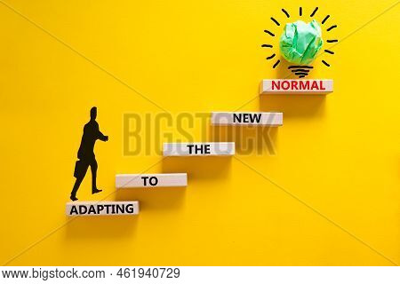 Adapting To The New Normal Symbol. Wooden Blocks With Words Adapting To The New Normal On Yellow Bac