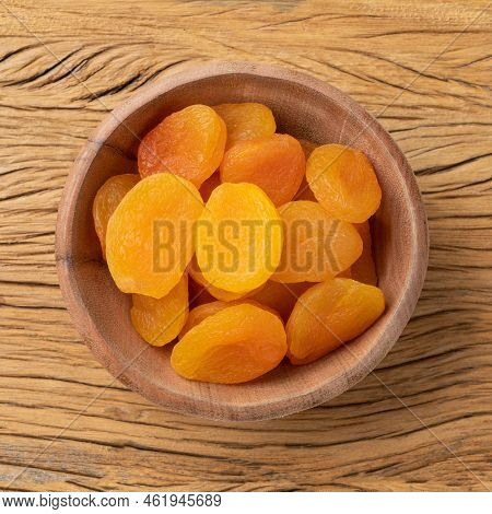 Dried Apricots In A Bowl Over Wooden Table.