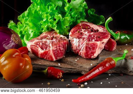 Raw Juicy Pork Steaks And Fresh Vegetables Before Cooking