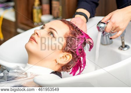 Washing Dyed Female Hair. A Young Caucasian Woman Having Her Hair Washed In A Beauty Salon. Professi