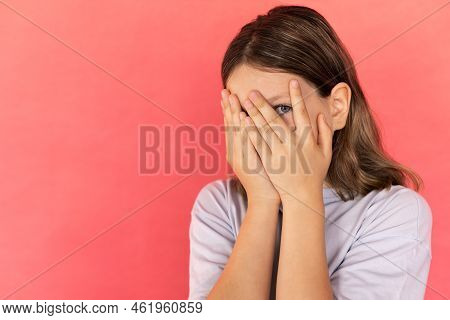 Portrait Of Frightened Preteen Girl Hiding Her Face In Hands. Caucasian Child Wearing Blue T-shirt L