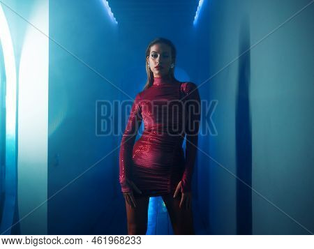 A Fashionable Photo Shoot With Tinted Blue, A Young Beautiful Model In A Scarlet Dress, In A Mysteri