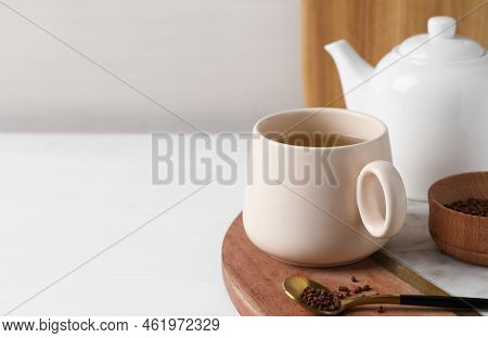 Cup Of Aromatic Buckwheat Tea And Granules On White Table. Space For Text