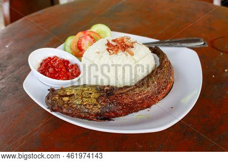 Indonesian Special Food. Close Up Pecel Catfish Served On A White Plate Placed On A Wooden Table