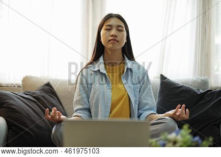 Calm Woman In Casual Look Meditaing, Practicing Yoga, Breathing, And Concentrating On Couch To Reduc