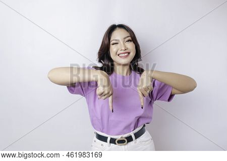 Excited Asian Woman Wearing Lilac Purple T-shirt Pointing At The Copy Space Downside Her, Isolated B